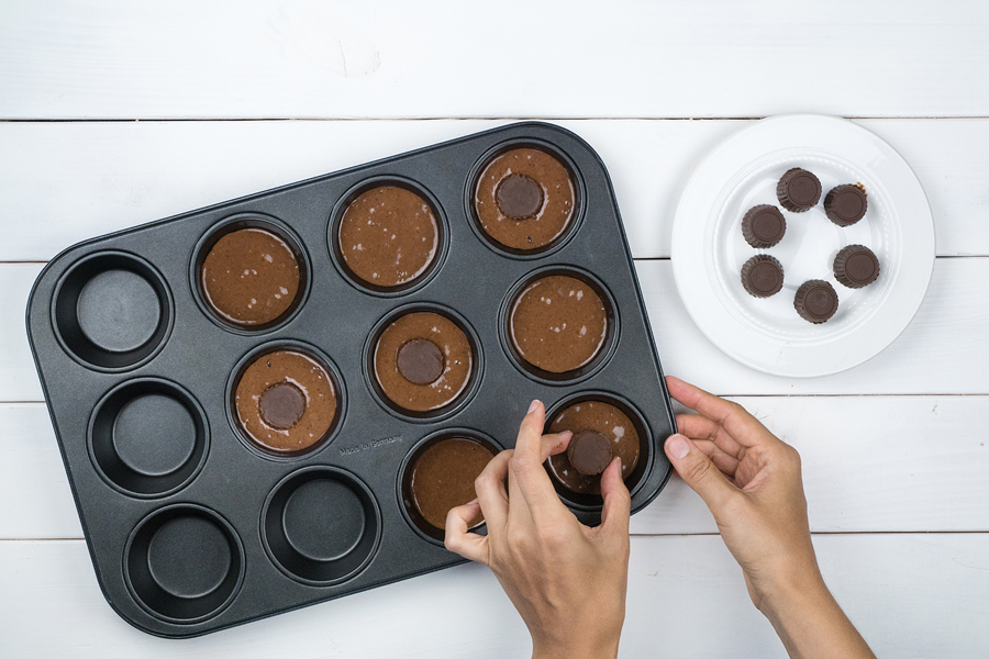 7.	Die Schokoladenpralinen jeweils mittig auf den Schokoteig im Muffinförmchen setzen. Dabei nicht eindrücken.