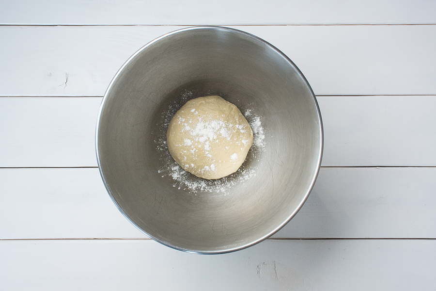 4. Den Teig mit Spannung zu einer Kugel formen. Eine Rührschüssel mit Mehl bestäuben und den Teig hineinlegen. Mit Mehl bestäubt und mit einem Küchentuch bedeckt über Nacht im Kühlschrank gehen lassen. 