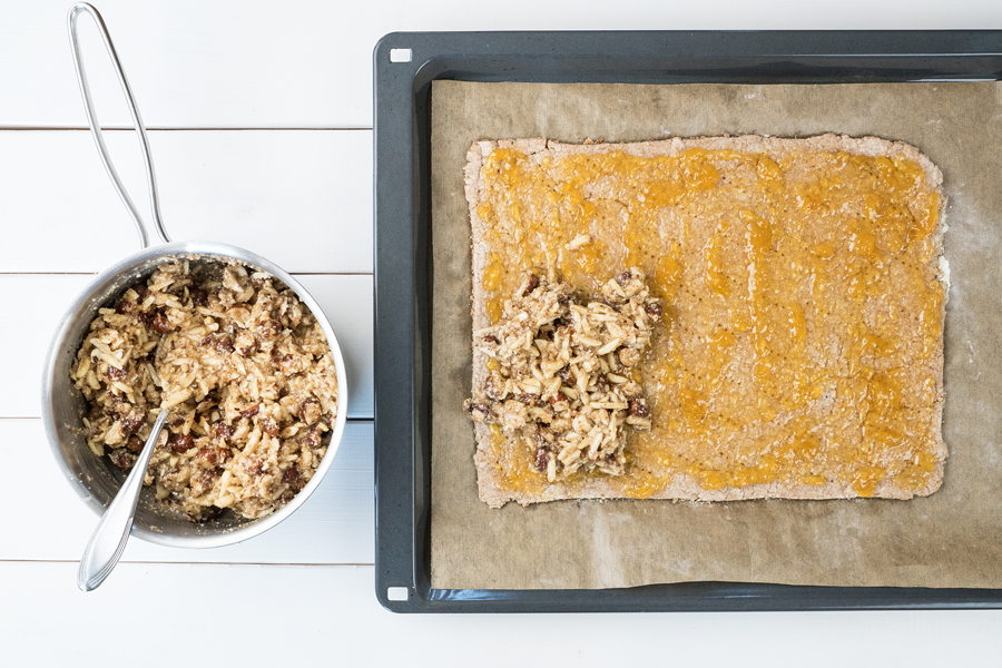 Die Nussmischung auf die Marmelade streichen, dabei fast bis zum Rand gehen. Die Nüsse laufen beim Backen noch ein wenig. Bei 180°C ca. 20 Minuten goldgelb backen, dann 10 Minuten abkühlen lassen.